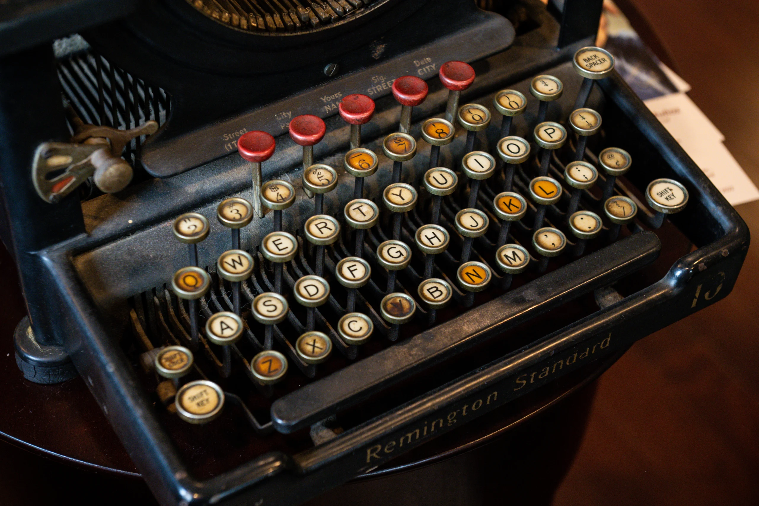Close-up of a vintage Remington Standard typewriter keyboard with round keys featuring letters, numbers, and symbols, set against a dark background.