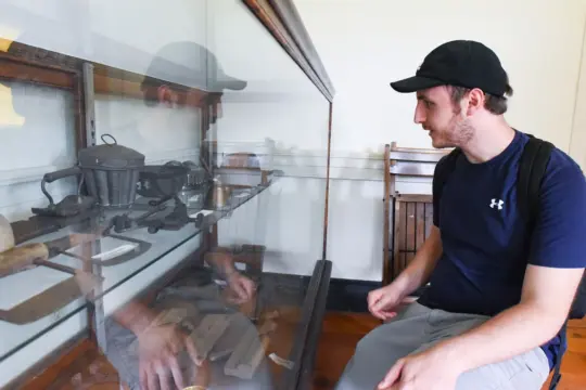 A Museum Studies student looking at historical artifacts displayed in a glass cabinet.