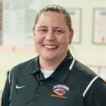 A person wearing a black polo shirt with a logo and text that says 