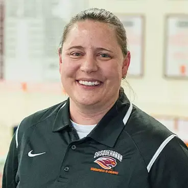 A person wearing a black polo shirt with a logo and text that says 