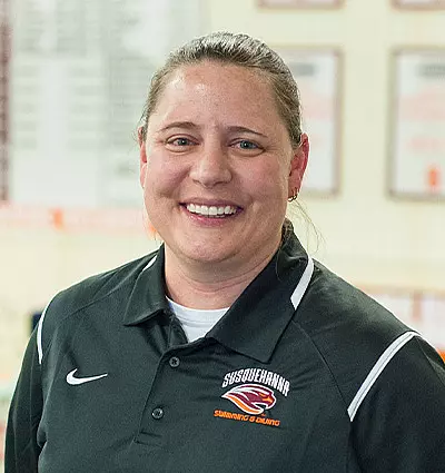 A person wearing a black polo shirt with a logo and text that says 