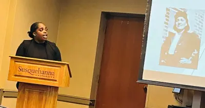 A person stands at a podium labeled 