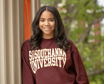 A person smiling while wearing a maroon sweatshirt with