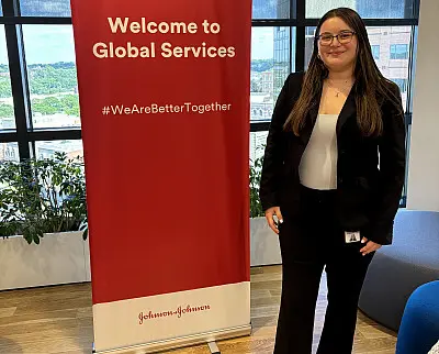 A person in business attire stands beside a red banner with the text 