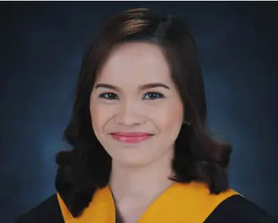 A portrait of a person with shoulder-length brown hair, wearing a black and yellow graduation gown, smiling against a dark blue background.