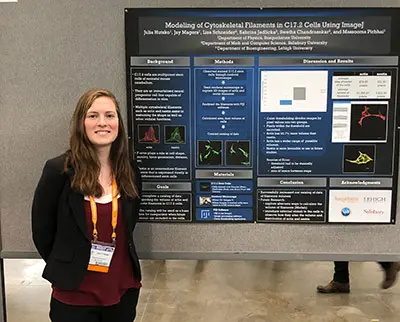 A woman stands beside a scientific poster titled 