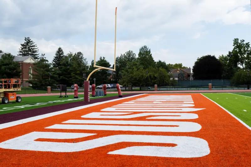 Close-up of a football field's end zone, featuring bright orange turf with the word 