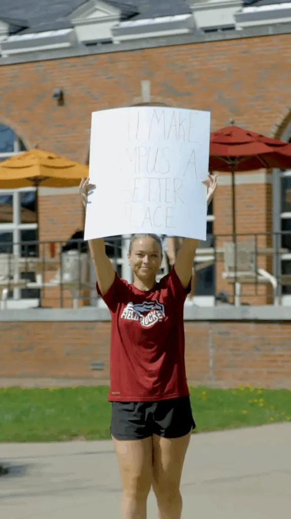 A person in a red shirt holds up a sign that reads