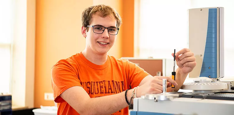 A young person wearing glasses and an orange 