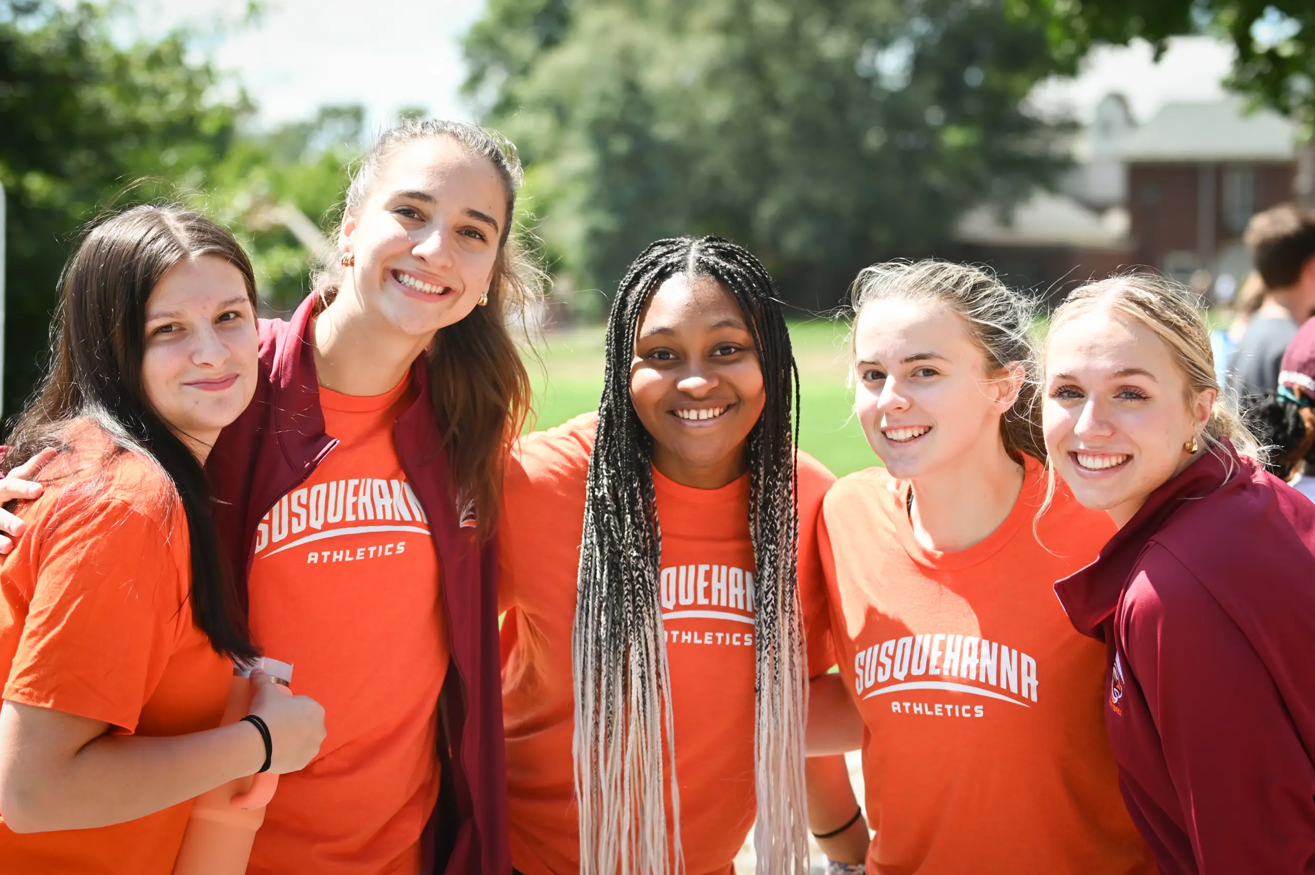 Five smiling young women wearing orange 