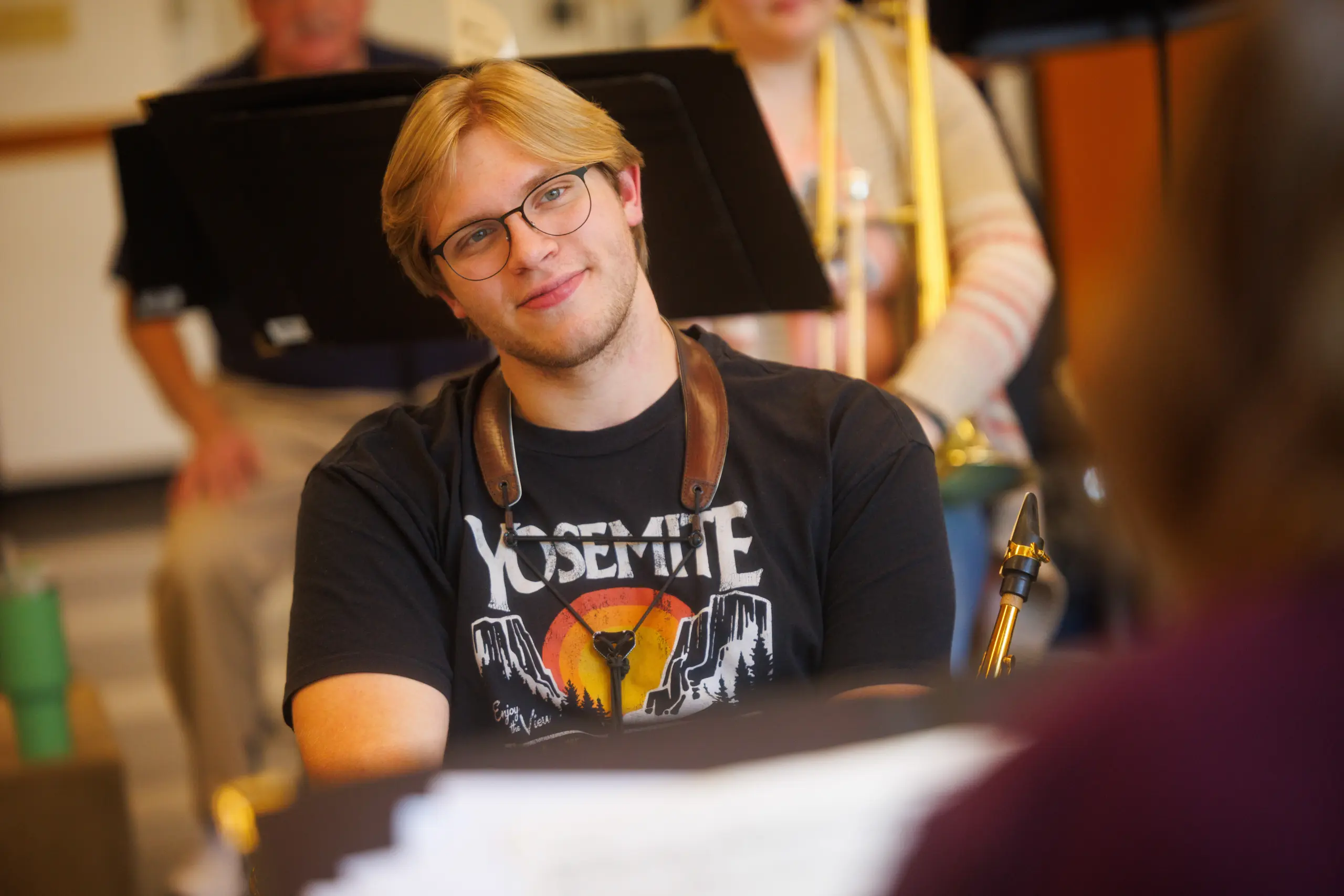 A young man with blond hair and glasses, wearing a 