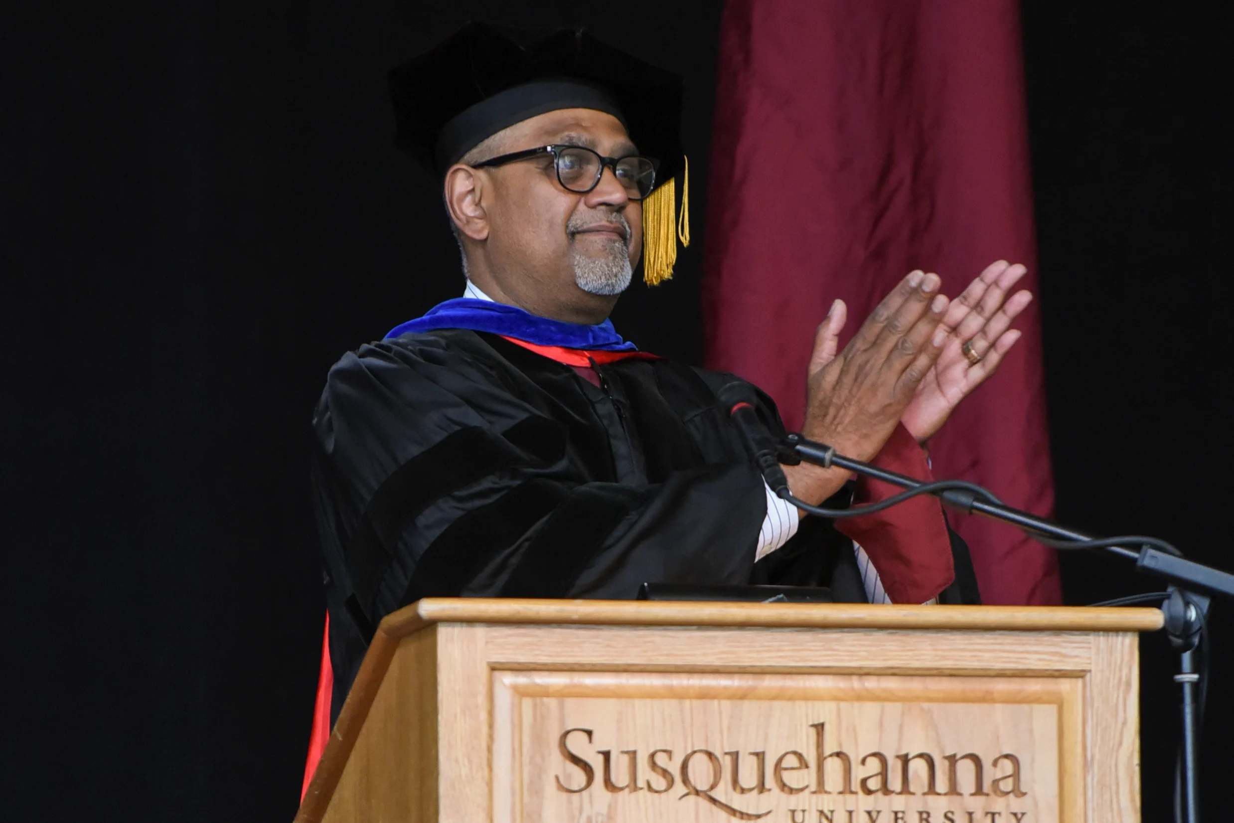 A person in academic regalia stands at a podium with 