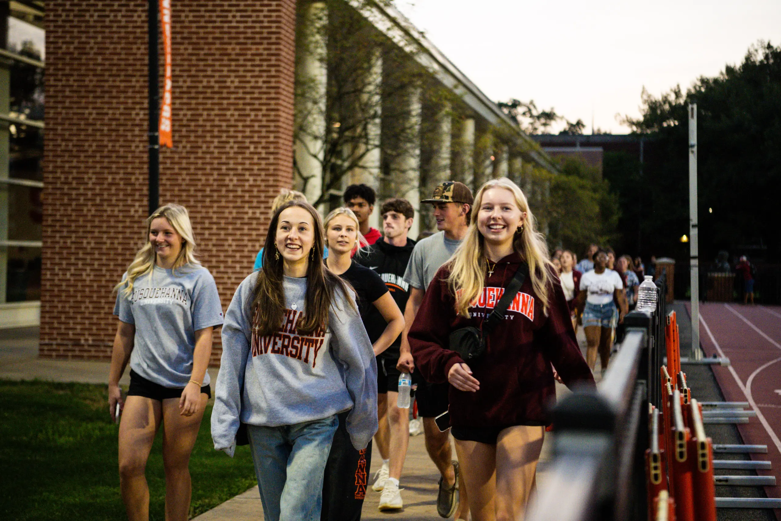 A group of smiling young adults, some wearing 