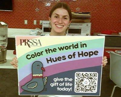A women holds a colorful sign that says