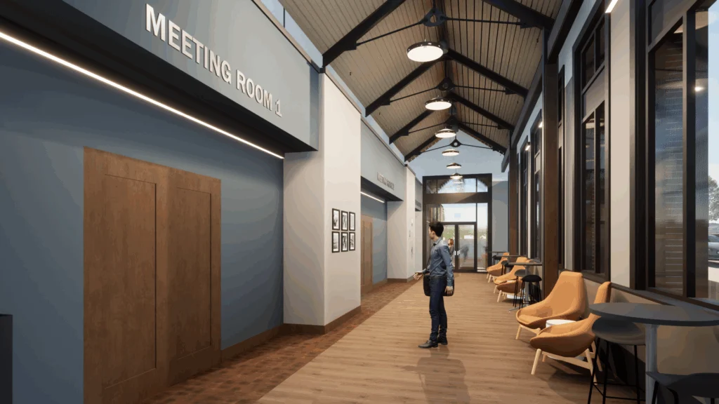 A person stands in a modern hallway with wood floors, high ceilings, and large windows—a testament to recent Campus Transformations. The sign for 